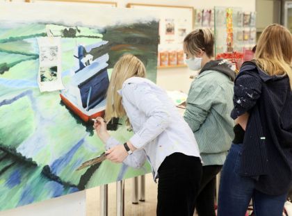 Drei Schülerinnen stehen vor einer Leinwand und malen