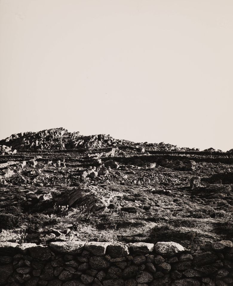 Die Fotografie Mykonos von Helmut Hahn zeigt eine steinige Landschaft unter einem ruhigen Himmel