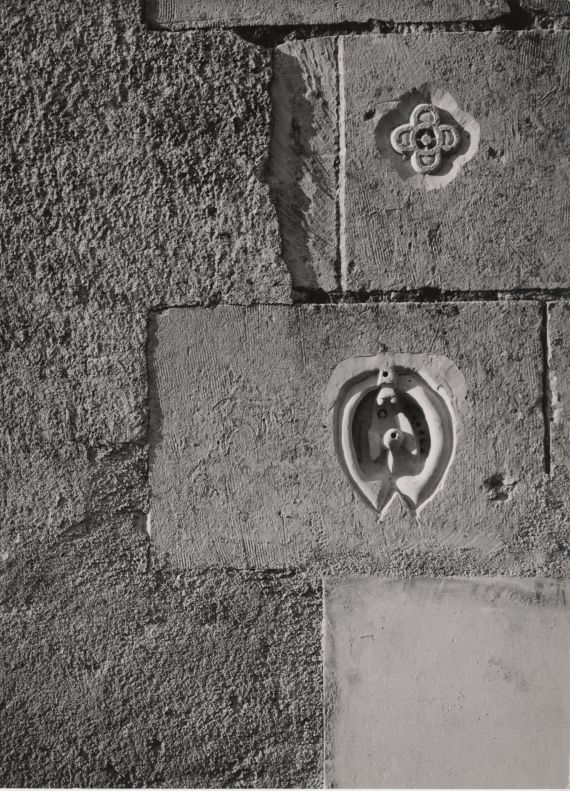 Die Fotografie Steinmarken für Dorothea Tanning und Max Ernst von Helmut Hahn zeigt eine Nahaufnahme einer Steinwand mit zwei kleineren, rundlichen Verzierungen