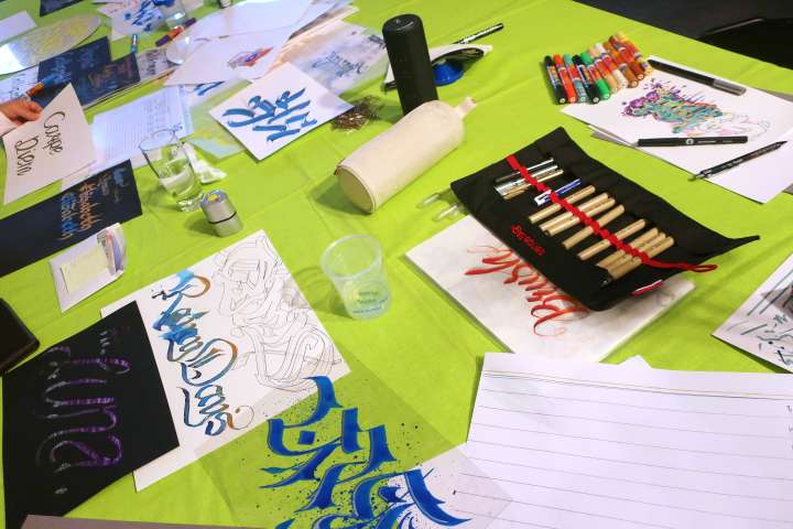 Die Fotografie zeigt einen Werktisch mit verschiedenen Utensilien zum calligrafieren.