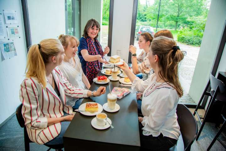 Eine junge Besuchergruppe genießt nach der Führung mit dem Guide in netter Runde Kaffee und Kuchen