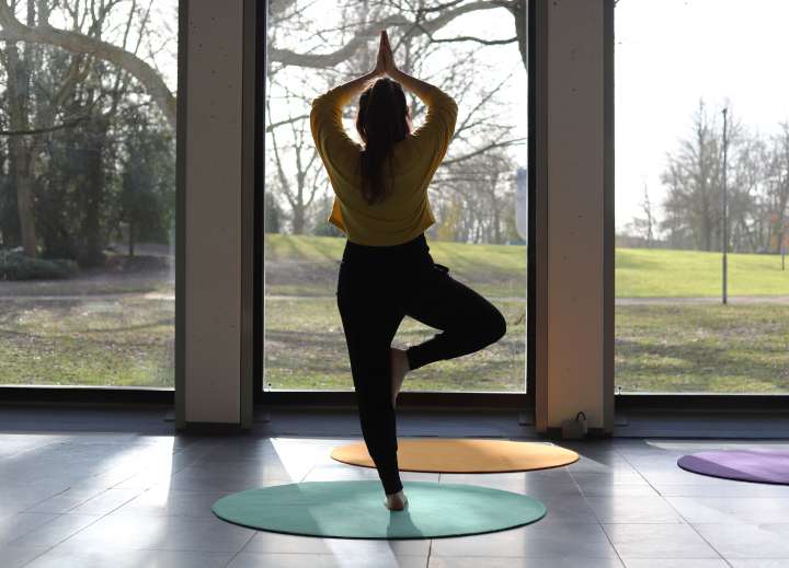 Die Fotografie zeigt eine Frau die Yoga im Clemens Sels Museum Neuss macht.